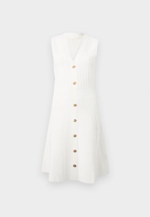 Bela pletena obleka brez rokavov z v-izrezom, navpično rebrasto teksturo in sprednjo vrsto sedmih rjavih gumbov od izreza do roba.