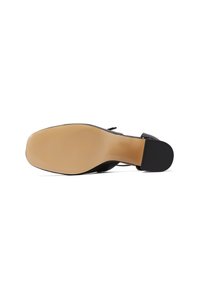 Chaussure noire à talon vue du dessous, avec une semelle beige, un talon bloc et une forme d'orteil carrée.