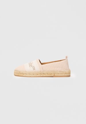 Světle růžové slip-on espadrilky s tkaninou s vaflovou strukturou, krémovým páskem s jemným textem a tkanou juteovou podrážkou proti bílému pozadí.