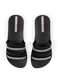 Schwarze Rutschen-Sandalen mit drei horizontalen Riemen, die mit klaren, glitzernden Akzenten verziert sind. Strukturierter Fußbett mit einem geprägten Muster.