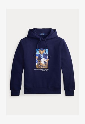 Marineblauwe hoodie met trekkoord, met een afbeelding van een beer in een matrozenoutfit zittend op een stoel met daaronder de tekst "Polo Bear by Ralph Lauren".