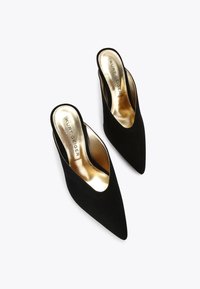 Decolletè slingback in suede nere con punta a punta, con soletta dorata con logo in rilievo. Tessuto liscio e design elegante.