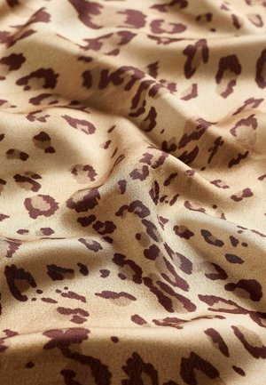 Țesătură cu imprimeu de leopard în bej cu pete maro, având o textură netedă și o cădere moale, creând cute și contururi naturale.