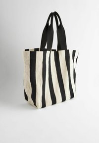 Gestreepte tote bag gemaakt van canvas, met afwisselend zwarte en crèmekleurige strepen, twee stevige zwarte handvatten, een open bovenkant en een zachte textuur.