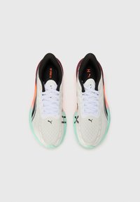 Weiße Sportschuhe mit einem strukturierten Mesh-Obermaterial, schwarzen und orangefarbenen Akzenten sowie einer mehrfarbigen Sohle mit mintgrünen und verlaufenden Farbtönen.