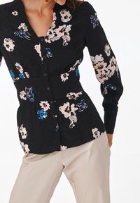 Black floral blouse with long sleeves, textured fabric, blue and pink flower patterns, button front, and a fitted waist design.