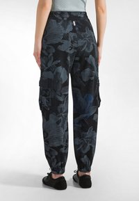 Sorte cargobukser med et blomsterprint i nuancer af blå og grå. Finesser inkluderer elastisk linning og ankellukkere samt cargolommer.