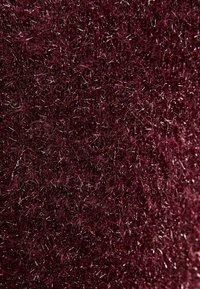 Bordowa tkanina o miękkiej, puszystej fakturze, z cienkimi metalicznymi nićmi wplecionymi w całość, tworzącymi migotliwy efekt.
