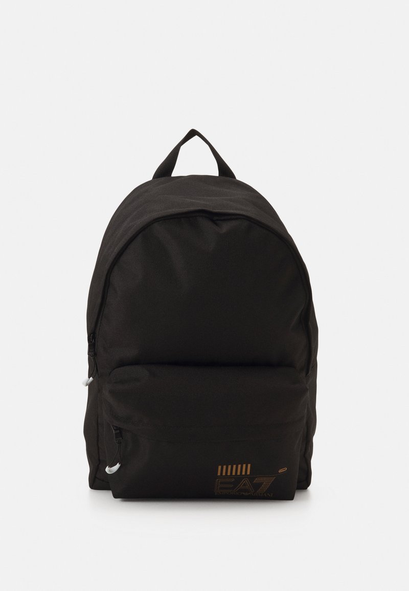 Rucsac din material textil negru, cu o formă rotunjită, buzunar frontal cu fermoar și un logo. Prezintă cusături rezistente și un mâner superior pentru transport.