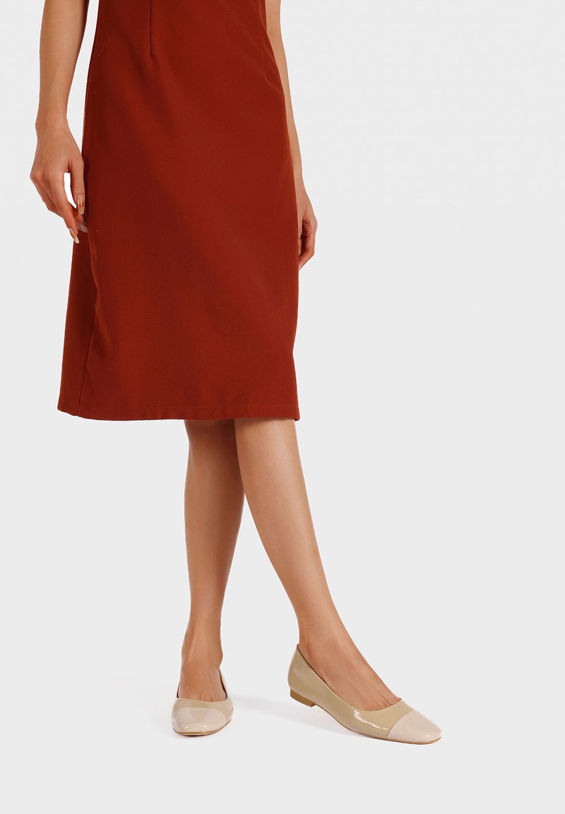 Ballerine in pelle lucida beige con punta rotonda e parte superiore opaca. La scarpa ha un tacco basso e un design elegante, adatta per l'abbigliamento casual.