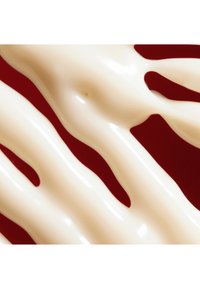 Krämig, glansig, off-white substans som flödar i vågiga mönster mot en solid mörkröd bakgrund. Slät textur med en svag glans.