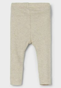 Leggings de canalé crema hechos de una tela suave. Presentan una cintura ajustada y piernas entalladas. Sin patrones visibles ni adornos.