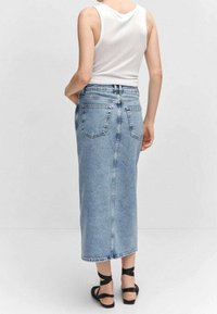 Vaaleansininen farkkuhame, jossa on korkea vyötärö, takataskut ja sivureikä. Yhdistetty tiukkaan valkoiseen tanktoppiin ja hihnallisiin mustiin sandaaleihin.