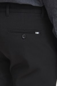 Pantalon noir en tissu lisse, avec une poche arrière à bouton et un détail de bande décorative. Un design à la fois élégant et fonctionnel.