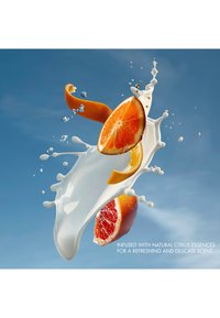 Orange and grapefruit slices with peel surrounded by white milk splashes, set against a blue background.