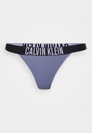 Calvin Klein stringtrosa i ljuslila ribbat tyg med ett svart elastiskt midjeband som visar varumärket i vit text.