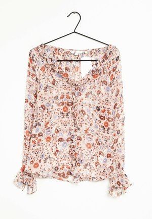 Blouse à manches longues avec col et poignets à volants, ornée d'un motif floral aux teintes de rouge, orange, violet et beige, suspendue sur un cintre noir.