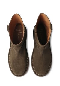 Para rjava semšena gležnjarja z detajli šivanja in svetlo rjavo notranjostjo, prikazana s ptičje perspektive na beli podlagi.