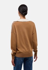 Pull en maille marron avec un col blanc et une coupe décontractée. Présente des épaules tombantes et des poignets côtelés, vu de dos.