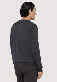 Tmavě šedý svetr vyrobený z měkké, texturované látky. Obsahuje kulatý výstřih a žebrované manžety a lem. Minimalistický design bez viditelných detailů.