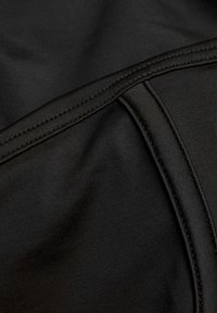 Prim-plan al unui material textil negru, evidențiind cusăturile și liniile de acelare detaliate pe un material neted, ușor elastic.