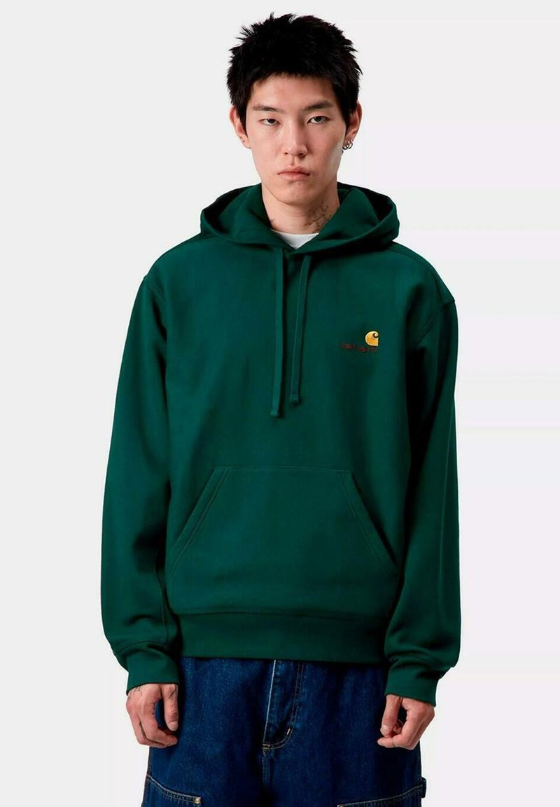 Sudadera con capucha verde y bolsillo delantero, con un pequeño logo naranja en el pecho. Está hecha de una tela suave y tiene un corte holgado.