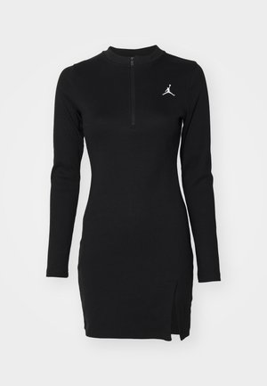Schwarzes, geripptes Kleid mit langen Ärmeln, hohem Kragen, halbem Reißverschluss und seitlichem Schlitz. Mit einem weißen Jordan-Logo auf der Brust.