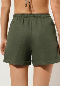 Grønne linnedshorts med elastisk talje og opfoldede manchetter. Stoffet har en let struktureret overflade, der giver en afslappet pasform.