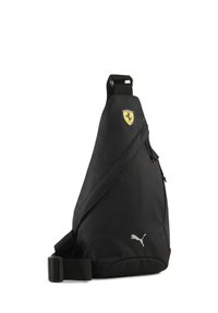 Sac bandoulière noir en tissu texturé, arborant un logo Ferrari jaune et un marquage Puma argenté. Compartiment zippé pour un rangement sécurisé.