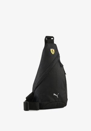 Melns sling soma, izgatavots no teksturētas auduma, ar dzeltenu Ferrari logotipu un sudraba Puma zīmolu. Kabata ar rāvējslēdzēju drošai glabāšanai.