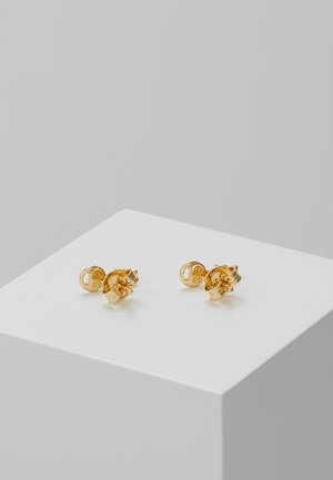 Paire de petites boucles d'oreilles en or clous avec fermoir papillon, marquées 925, exposées sur un cube blanc sur fond gris.