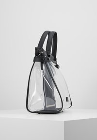 Borsa trasparente con dettagli in pelle nera, forma triangolare strutturata, manici doppi e hardware argentato per un design moderno.