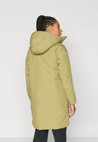 Olijfgroene gewatteerde jas met capuchon, met een ontwerp van verticale naden en zijopeningen voor bewegingsvrijheid. Soepele, gestructureerde stof.