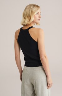 Czarny dzianinowy top na ramiączkach z wycięciem na plecach typu racerback, z dopasowanym tułowiem i prążkowaną fakturą, zestawiony z jasnoszarymi, dopasowanymi spodniami.