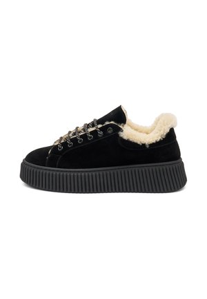 Zapatilla de ante negra con un forro de crema esponjoso, suela plana negra y ojales en tono plateado. Presenta una suela texturizada acanalada y cordones redondos.