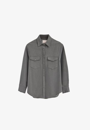 Chemise en denim gris à manches longues, avec un devant boutonné, deux poches poitrine et un col pointu. Texture lisse et coupe décontractée.