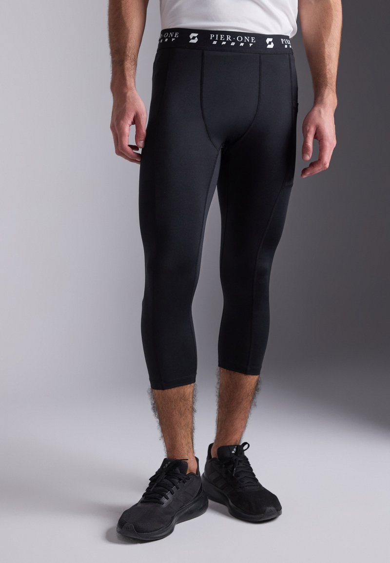 Schwarze Sportleggings mit enganliegendem Design, elastischem Taillenbund mit der Aufschrift "PIER-ONE SPORT" und glatter, matter Textur. Strickstoff.