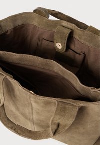 Brown suede tote bag with double handles, open top, inner fabric lining, an inner pocket, and a snap button closure strap.