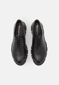 Scarpe in pelle nera con finitura liscia, punta tonda e allacciatura evidente. Suola in gomma spessa con trazione, soletta con marchio visibile. Misura 37.