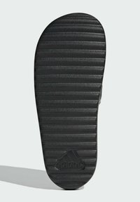 Black rubber sandal sole with horizontal ridges for traction. Features Adidas logo embossed on the heel. Flat design for easy wear.
