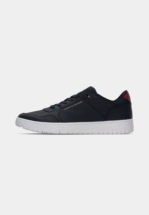 Laag uitgesneden marineblauwe sneaker met een witte zool, vetersluiting, rode hiel detail en een klein Tommy Hilfiger-logo aan de zijkant.