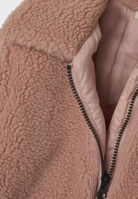 Giacca in pile rosa con un'esterno morbido e testurizzato, dotata di chiusura frontale con zip e rivestimento interno liscio.