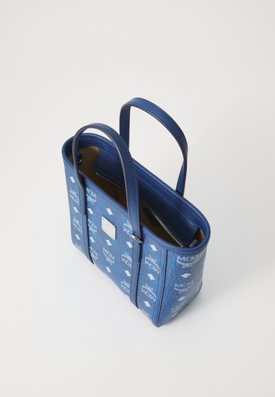 Sac à main bleu avec design structuré, doté d'un extérieur texturé, de deux poignées et d'une poche intérieure zippée. Motifs de logo sur l'ensemble.