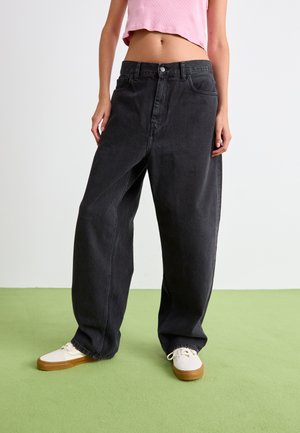 Black wide-leg jeans made of denim, featuring a high waist, front button closure, and subtle faded texture. Paired with white sneakers.