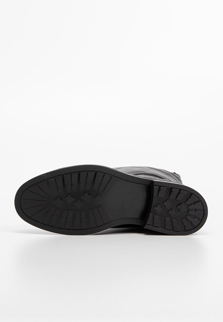 Schwarze Lederstiefelsohle mit einem strukturierten Profilmuster. Verfügt über eine konturierte Form und ein langlebiges Gummi-Material für Traktion und Unterstützung.