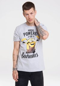 Grey cotton t-shirt featuring a Minion graphic with "POWERED BY Bananas" text. Short sleeves, round neckline, and a relaxed fit.