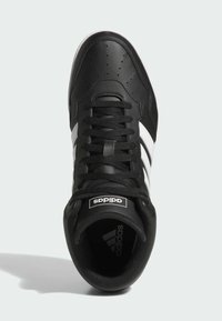 Zapatilla de cuero negra con rayas blancas, puntera redonda, detalles perforados, cordones negros y lengüeta con marca. Suela texturizada.