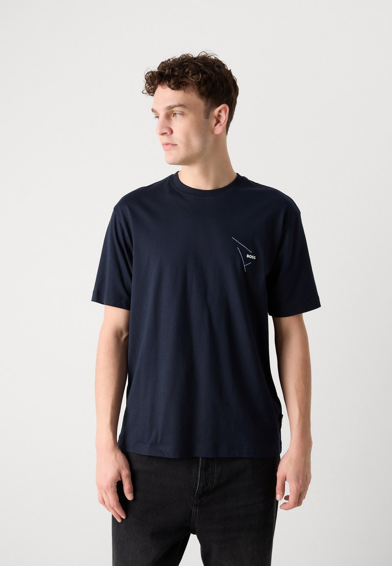 Camiseta de algodón azul marino de manga corta con un pequeño logo blanco en el pecho. Cuello redondo clásico y corte relajado.