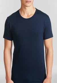 Maglietta blu navy a maniche corte realizzata in cotone, con colletto rotondo e una texture liscia e uniforme. Nessun motivo o accentuazione visibile.
