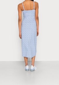 Modré květované midi šaty s tenkými ramínky, přiléhavým živůtkem a rozšířenou sukní. Nošeny s světle modrými teniskami s průhlednou podrážkou.